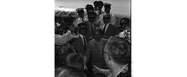 Perry Como scende dalla scaletta di un aereo circondato da una gran folal di gente - piano americano