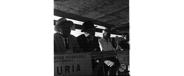 Quattro giurati, il secondo con una bombetta in testa, seduti sul palco in occasione di una gara ippica internazionale a Santa Marinella - piano medio