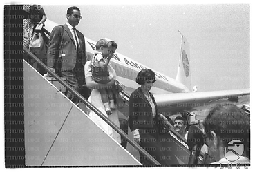 Gina Lollobrigida ripresa mentre scende dalle scalette dall'aereo della Pan American Airways seguita dalla nurse con il figlio Igor e dal marito Milko - totale