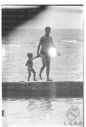 Un uomo ed un bambino in costume ripresi sul molo di Santa Marinella - totale