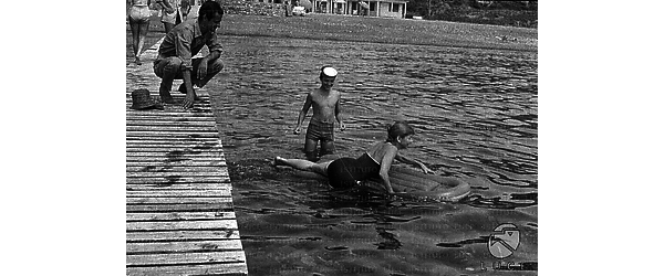 Serge Reggiani su un molo a passerella, mentre la moglie Annie Noel e il figlio Stephan sono in mare