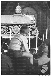 I funerali di Pio XII all'interno della basilica di San Pietro; un bambino sulle spalle del padre - piano americano