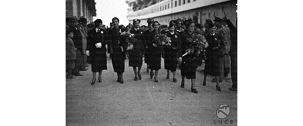 Napoli Un gruppo di falangiste, tra cui Pilar Primo de Rivera, cammina, con mazzi di fiori in mano, lungo il molo a cui è attraccata la nave "Rex"