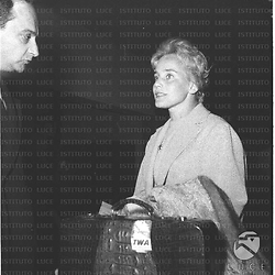 Maria Schell è ritratta con la propria valigia, accanto a un uomo. Mezza figura
