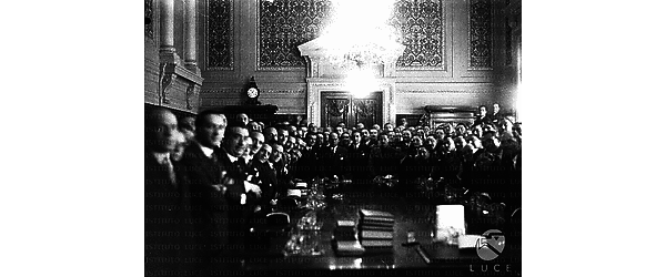 Foto di gruppo in una sala del Viminale. Mussolini  con gli arbitri di calcio in piedi intorno ad un tavolo di lavoro. Campo medio