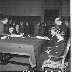 Seduti ad un tavolo il ministro Martino, con altri personaggi politici, che firma l'accordo di emigrazione. Di fronte ai rappresentanti del governo italiano ci sono i politici tedeschi che firmano . Campo medio