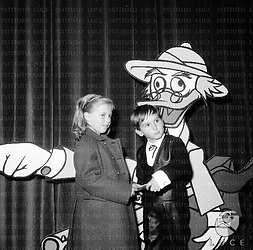 Il figlio di Gina Lollobrigida ed un'altra bambina davanti alla gigantografia del personaggio dei cartoni animati Pico de Paperis - piano americano