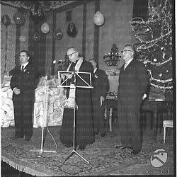 Don Rossi tiene un discorso in occasone del pranzo per la Befana offerto ai bambini poveri della capitale; con lui Luigi Turchi (a sinistra) e Franz Turchi (a destra) - totale