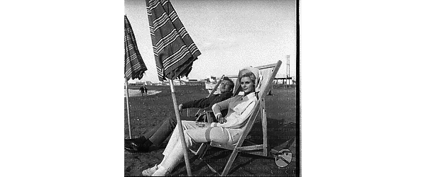 Miss Finlandia e un uomo seduti su due sdraio sul litorale romano - totale