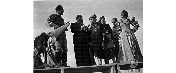 Castello di Gradara Luis Trenker e Laura Nucci, in abiti di scena, sono in piedi su un palco improvvisato con Rachele Mussolini e Paulucci di Calboli durante le riprese del film "Condottieri"