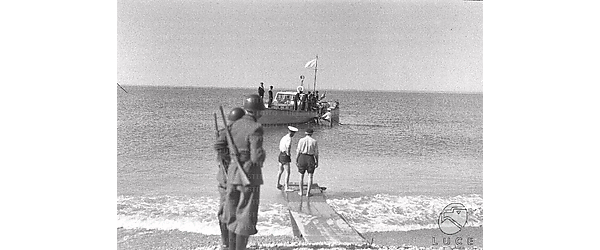 Ventimiglia-Mentone Una motovedetta con bandiera bianca si avvicina alla spiaggia attesa da due soldati e da due marinai su una banchina di legno