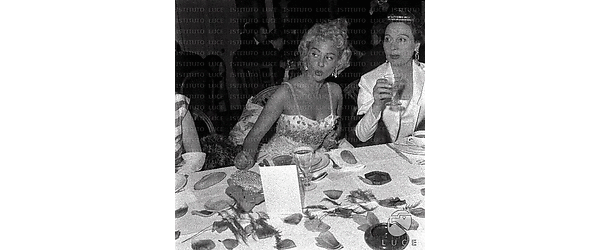 Martine Carol a tavola, seduta accanto ad una donna bruna (attrice?)
