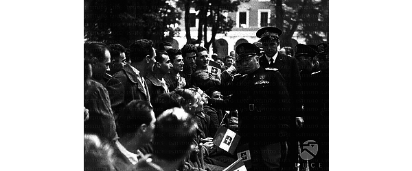 Bologna Nel giardino del centro ortopedico "Putti",Benito Mussolini, accompagnato da altre autorità, saluta un gruppo di giovani soldati che hanno bandierine tricolori in mano