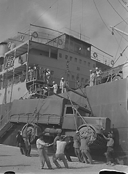 Un camion dell'esercito italiano viene scaricato da una gru su uno dei moli del porto di Durazzo con l'aiuto di soldati e marinai