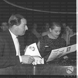 Eleonora Rossi Drago, seduta in platea accanto a un uomo - il marito (?) -, legge un depliant attendendo l'inizio dello spettacolo. Piano medio