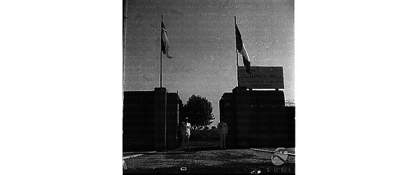 Due vigili urbani ai piedi del cancello d'ingresso del palazzetto dello sport in vista delle olimpiadi del 1960. Campo lungo