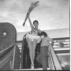 Vera Tschechowa ripresa in cima alla scaletta dell'aereo con un bambino accanto e fiori in mano - totale