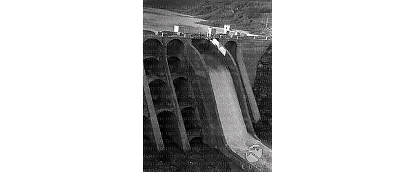 Veduta dell'impianto di sbarramento delle acque, dal quale esce una cascata d'acqua regolata per la produzione dell'energia idroelettrica. Scorcio dall'alto. Particolare