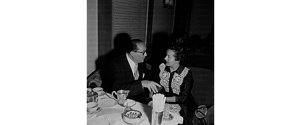 Henry Koster seduto al tavolo di un locale accanto ad una donna - piano americano