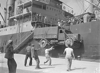 Marinai e civili impegnati a scaricare un camion militare da una nave