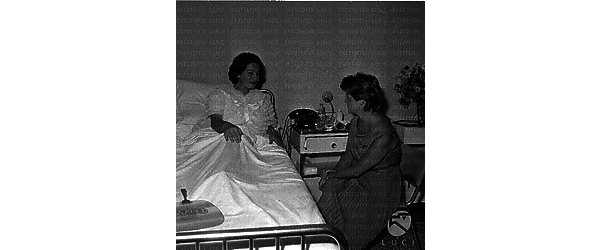 Nicoletta Orsomando, distesa nel letto di una clinica, conversa con Franca Vecchi seduta al suo fianco; totale