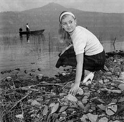 Alessandra Panaro piegata in basso vicino ad un lago
