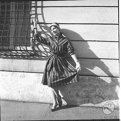 Una modella con un vestito a strisce posa in una strada di Roma. Campo medio