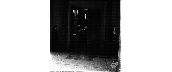Due suore in un corridoio con una porta aperta da cui si intravede la sala congressi. Totale