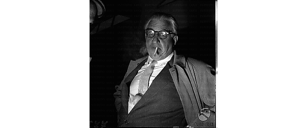 Il regista e produttore David O. Selznick all'aeroporto di Ciampino mentre si fuma una sigaretta - piano americano