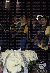 Un cuscino di fiori bianchi a forma di cuore, Stefania Adami con gli occhiali scuri, tra i banchi della chiesa tra le persone della protezione civile