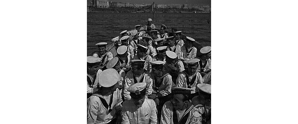 Un folto gruppo di marinai a bordo di una scialuppa della Vittorio Veneto in navigazione fra il lungomare di Taranto e la nave