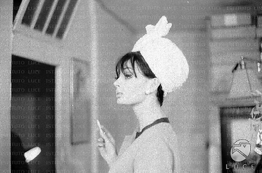 Barbara Steele ripresa di profilo in un negozio di cappelli mentre ne prova un tipo - piano medio