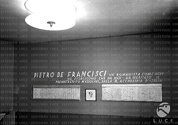 Parete di sala espositiva intitolata a Pietro De Francisci per il Diritto Romano. Al centro della parete un ritratto grafico del 'romanista'. Totale