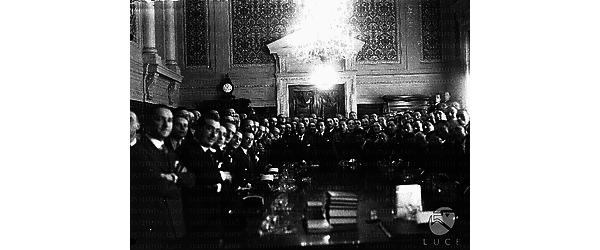 Foto di gruppo in una sala del Viminale. Mussolini  con gli arbitri di calcio in piedi intorno ad un tavolo di lavoro. Campo medio
