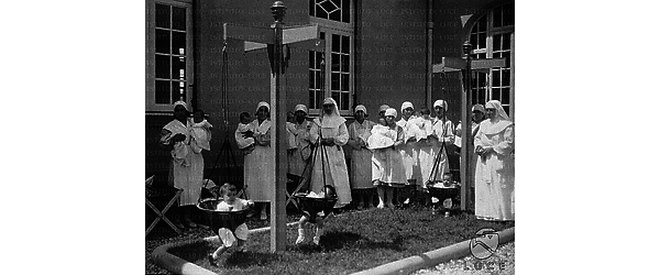 Palermo Un gruppo di suore e infermiere della Casa del Sole posa vicino a tre bimbi sistemati in strutture per l'apprendimento della deambulazione