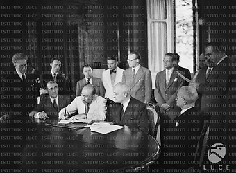 Roma Mr. Taft (?), seduto tra l'ambasciatore Dunn e il ministro Del Vecchio in una sala del Ministero delle Finanze,  firma un accordo sulla cessione di beni americani all'Italia