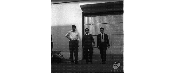 Tre uomini ripresi in un esterno, davanti ad un edificio, forse uno dei capannoni dove è in parte ospitato il laboratorio di fisica di Frascati - campo medio
