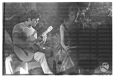 Una giovane accompagnata da un chitarrista ripresa in giardino durante la festa a casa Roloff - totale