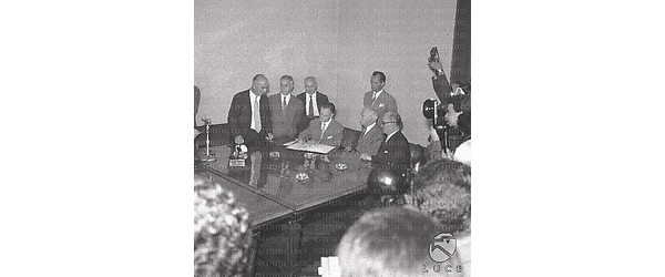 Personalità riunite attorno ad un tavolo per la firma delle carte per la ricostruzione della nave; il primo in piedi a sinistra è Manzitti; Lombardi firma il contratto; l'ultimo seduto a destra è Fascetti - campo medio