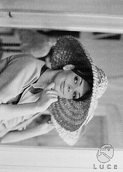 Barbara Steele ripresa in un negozio di cappelli mentre ne prova un tipo - medio primo piano