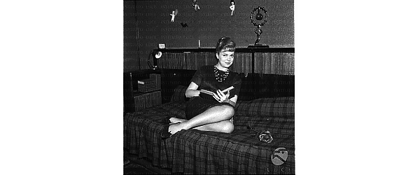 Ketty Della Porta sdraita su un divano con un libro in mano. Totale