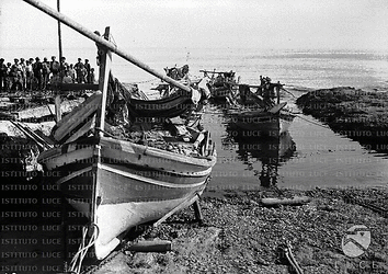 Il porticciolo di Isola delle Femmine con barche e pescatori raccolti sul molo. Campo lungo