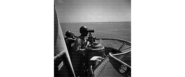 Marinai scrutano l'orizzonte col binocolo da una torretta di osservazione