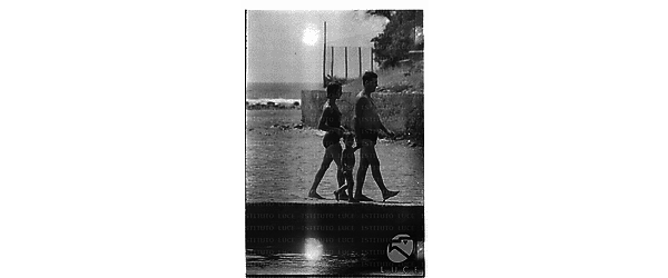 Un uomo, una ragazza ed un bambino ripresi in costume sul molo di Santa Marinella - totale