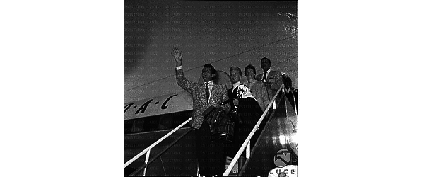 Dean Martin saluta dalla scaletta dell'aereo, accanto a lui una donna, forse la moglie - piano americano