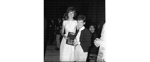 Rita Pavone in posa con una ragazza: mostrano un premio - piano americano