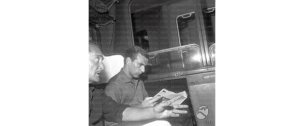Angelillo legge un giornale seduto nello scompartimento del treno