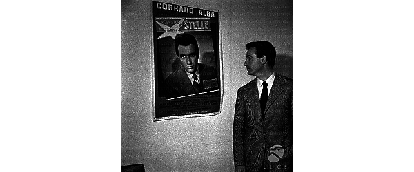 Corrado Alba guarda un  manifesto pubblicitario di "Polvere di stelle"