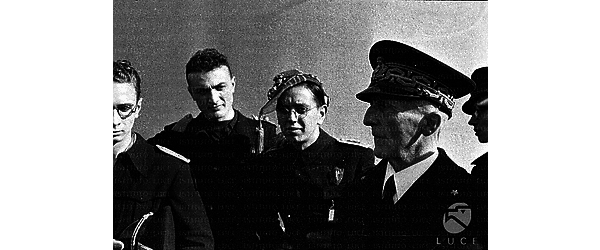 Inq. frontale a mezzo busto di universitari fascisti in visita a una nave da guerra. Tra loro è ritratto, di profilo, un anziano ammiraglio - campo medio, orientamento orizzontale