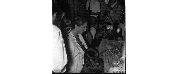 Silvana Mangano, seduta di profilo e attorniata dai fotografi, mentre il parrucchiere le taglia i capelli per il film "Jovanka e le altre" - piano americano